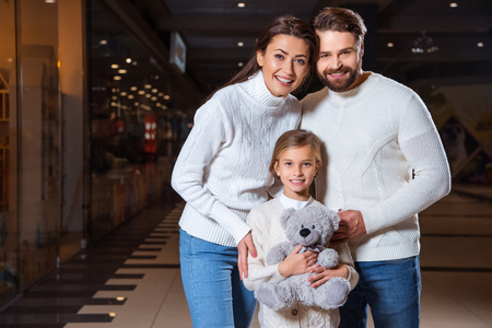 portrait of happy parents and daughter with teddy bear looking at cameraの写真素材