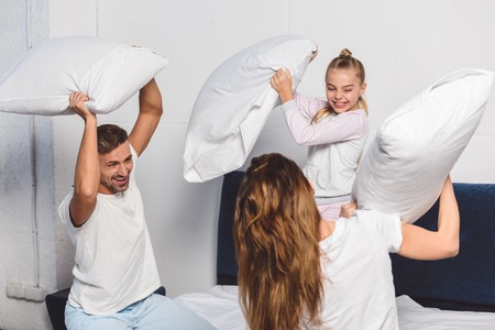 Cheerful family having pillow fight in bedroomの写真素材