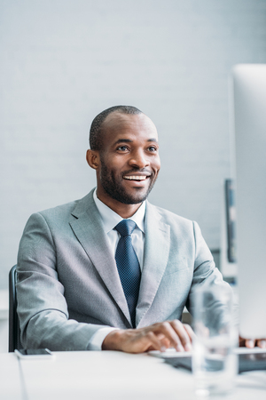 portrait of smiling african american businessman working on computer at workplaceの写真素材