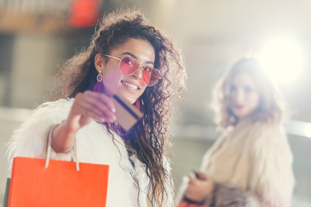 young stylish woman in fur coat with golden credit card on shoppingの写真素材