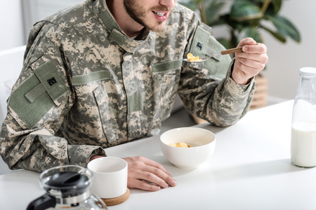 cropped view of man in camouflage uniform having breakfast in morningの写真素材