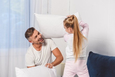 Father and daughter having pillow fight at homeの写真素材
