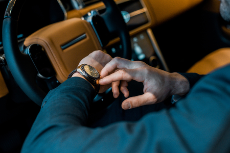 cropped image of businessman checking watch in luxury carの写真素材
