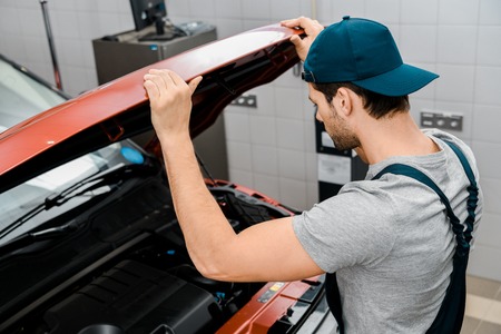 side view of auto mechanic examining car cowl at workshopの写真素材