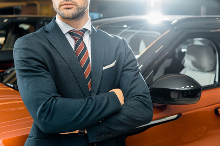 partial view of businessman posing with crossed arms near automobileの写真素材