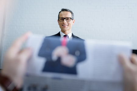 selective focus of smiling businessman and colleague with newspaperの写真素材