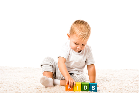 cute toddler boy playing colored cubes with letters on carpet isolated on whiteの写真素材