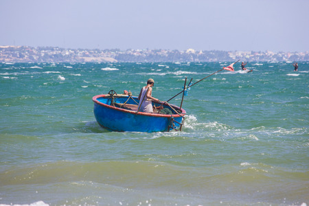 back view of fisherman in round boat floating on waves, Vietnam, Mui Neの写真素材