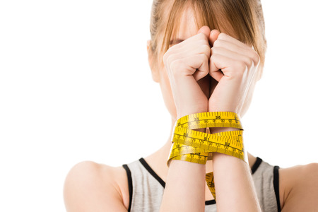 Woman covering face with hands tied in measuring tape isolated on whiteの写真素材