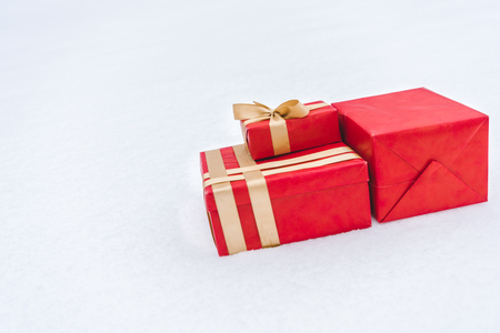 Close-up view of red gift boxes wrapped with golden ribbons on snowの写真素材