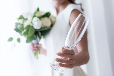 Selective focus of bride with wedding bouquet holding empty champagne glassの写真素材