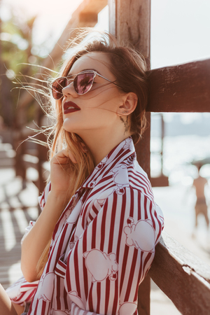 Close-up portrait of sensual young woman leaning back on pier at beachの写真素材