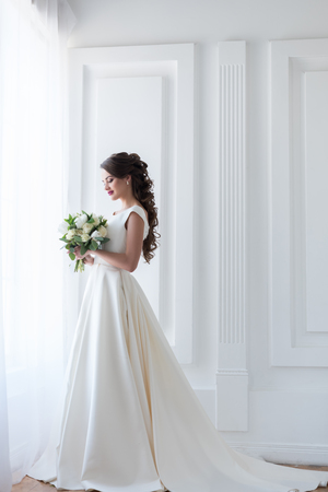 Bride posing in elegant white dress with wedding bouquetの写真素材