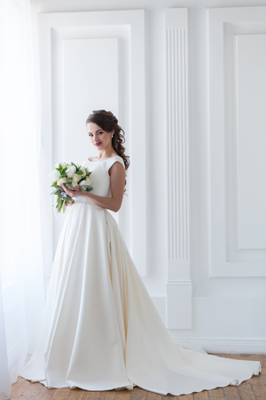 Smiling bride posing in elegant dress with wedding bouquetの写真素材