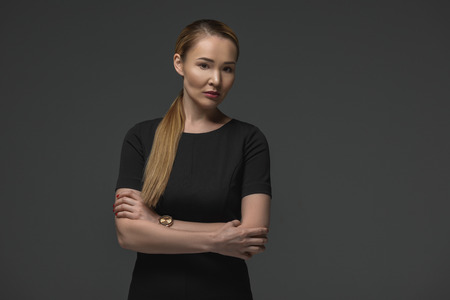 Portrait of beautiful Kazakh woman with crossed arms looking at camera isolated on greyの写真素材