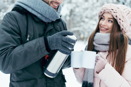 Partial view of couple drinking tea from thermos in winter parkの写真素材