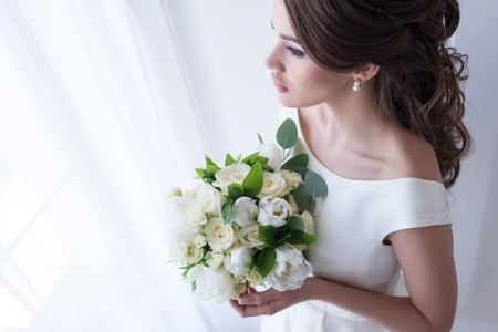 attractive bride in traditional dress holding wedding bouquetの写真素材