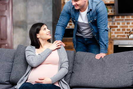 cropped shot of happy young pregnant couple smiling each other at homeの写真素材