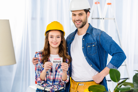 smiling couple in helmets holding home repair cardの写真素材