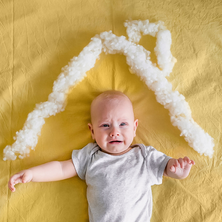 top view of adorable infant child under house roof made of cotton in bed