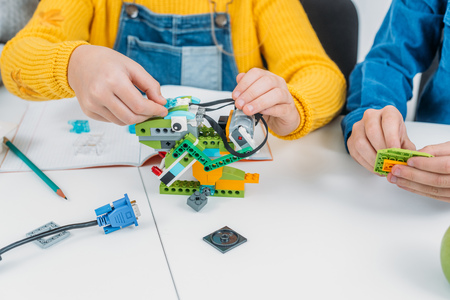 cropped view of children working together on STEM project in classrom