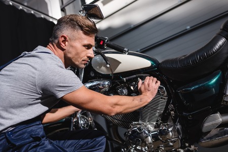 mechanic checking motorbike engine in garageの写真素材