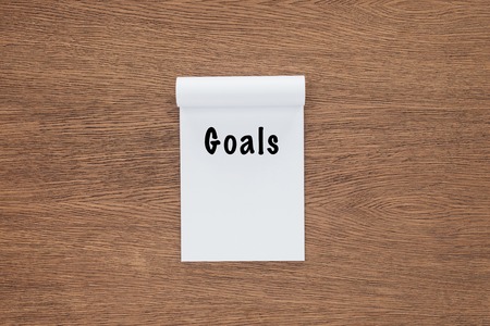 top view of notebook with 'goals' lettering on wooden backgroundの写真素材