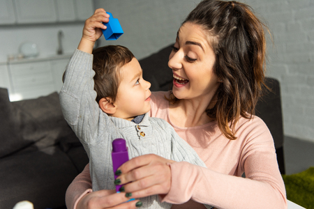 happy little boy and his mother playing with colorful plastic blocks at homeの写真素材
