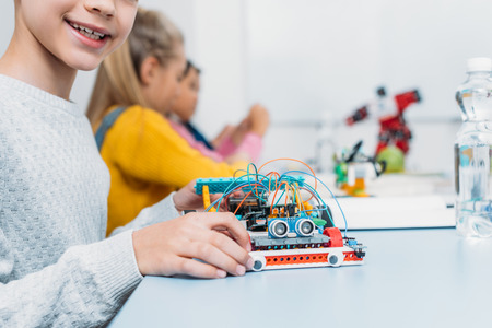 cropped view of schoolboy holding handmade robot model and classmates working together on project during STEM lesson on backgroundの写真素材