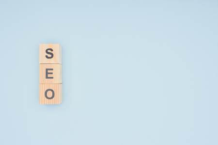 Flat lay of wooden blocks with seo lettering isolated on light blue
