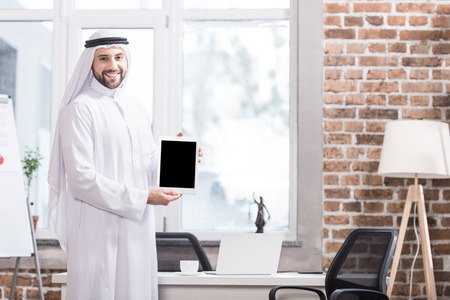 Arabian businessman holding digital tablet in modern officeの写真素材