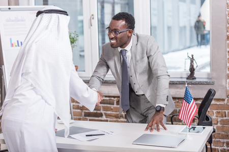 African american businessman shaking hands with arabic partner in officeの写真素材