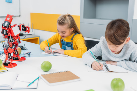 attentive children writing at STEM robotics lesson