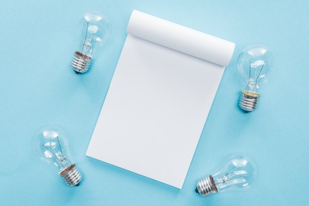 top view of blank notebook with light bulbs on blue background, having idea conceptの写真素材