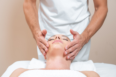 Male therapist doing face massage to womanの写真素材
