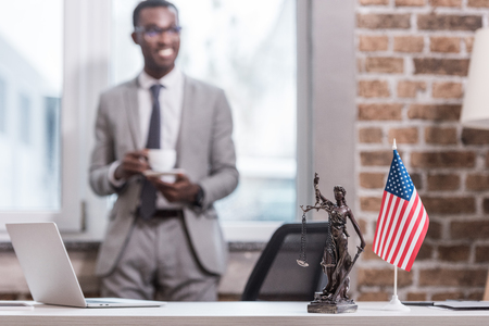 Office desk and objects with african american businessman on backgroundの写真素材