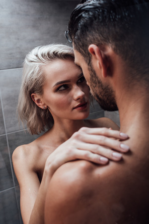 beautiful young woman passionately looking at man in showerの写真素材