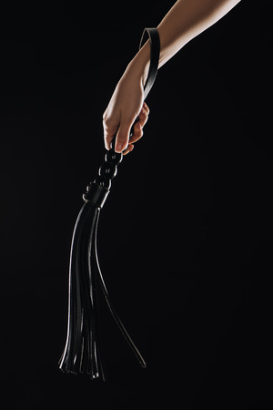 cropped view of female hand holding leather flogging whip isolated on black