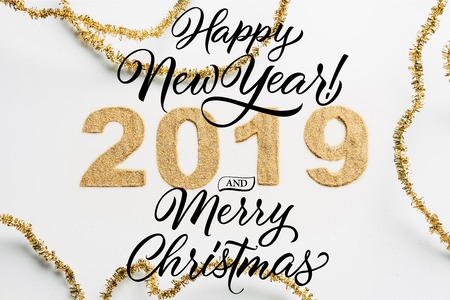 top view of 2019 year sign made of golden glitters and garlands on white backdrop with happy new...