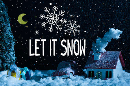 close-up shot of toy car with christmas gifts and house covered with snow at night, with "let it snow" lettering with snowflakesの写真素材