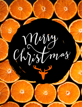 full frame of arranged cut tangerines halves on black background with "merry christmas" lettering with deer headの写真素材