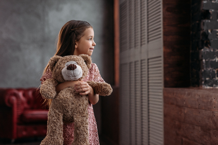 beautiful little child holding teddy bear at homeの写真素材