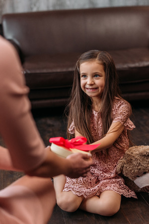 mother giving birthday gift to happy little daughterの写真素材