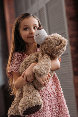 adorable little child embracing teddy bear at homeの写真素材