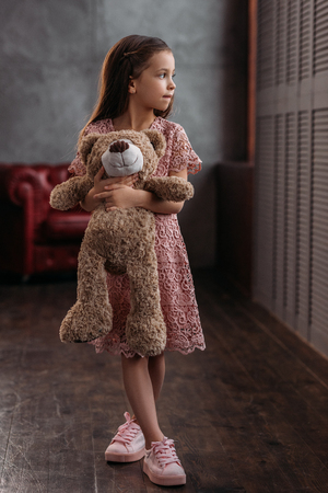 beautiful little child holding teddy bear at loft apartmentsの写真素材