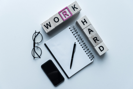 overhead view of wooden cubes with words Work Hard and notebook on tableの写真素材
