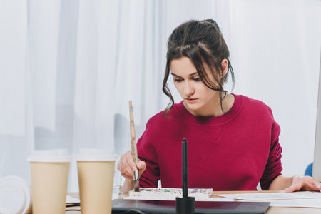 Attractive young girl working on illustrations in home officeの写真素材