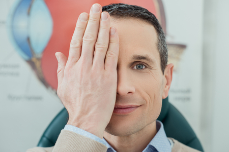 obscured view of smiling man getting eye test in clinicの写真素材