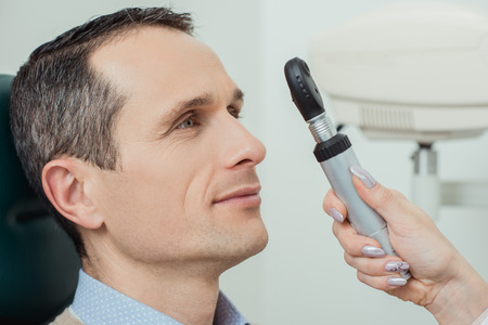 side view of man getting eye test by ophthalmologist in clinicの写真素材