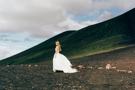 beautiful young bride in white wedding dress walking at amazing icelandic natureの写真素材